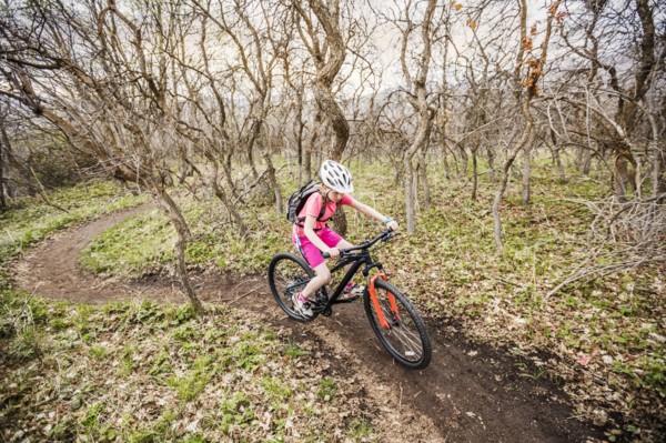 Caucasian girl riding bicycle on forest path