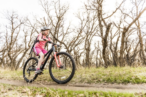 Caucasian girl riding bicycle on forest path