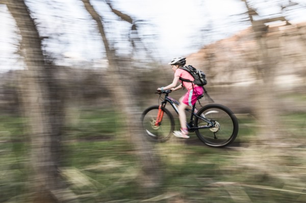 Caucasian girl riding bicycle on forest path