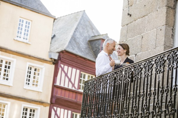 Caucasian couple drinking coffee on balcony in city