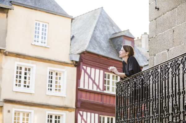 Caucasian woman drinking coffee on balcony in city