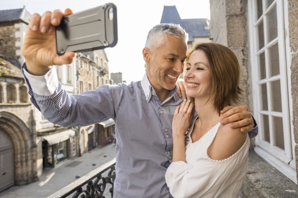 Caucasian couple posing for cell phone selfie