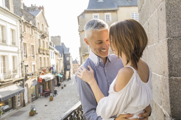 Caucasian couple hogging on balcony in city