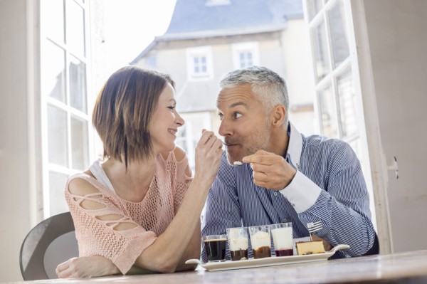 Caucasian woman feeding man dessert in restaurant