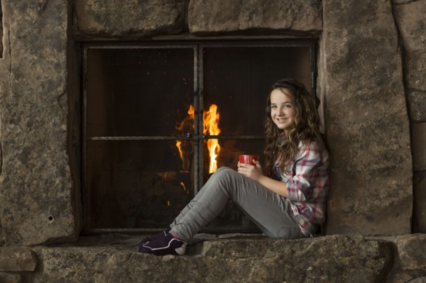 Smiling Caucasian girl sitting near fireplace