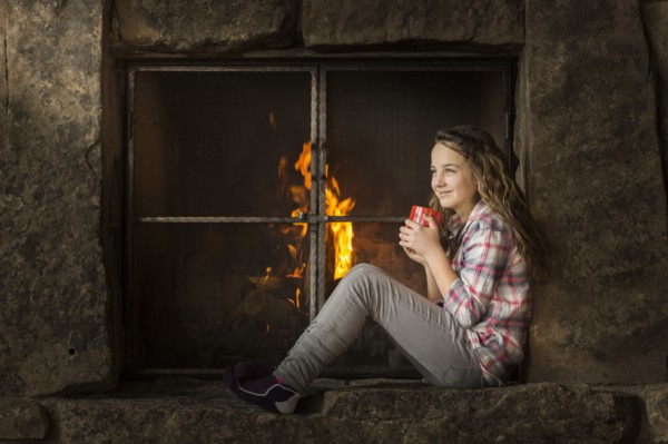 Smiling Caucasian girl sitting near fireplace