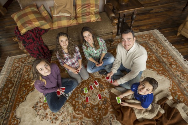 Portrait of smiling Caucasian family sitting on rug playing card game