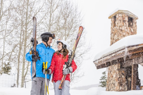 Smiling Caucasian couple holding skis at resort