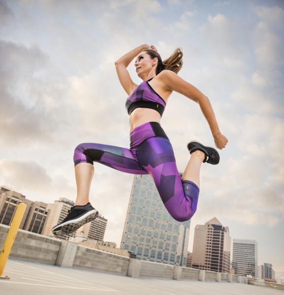 Caucasian woman running and jumping on urban rooftop