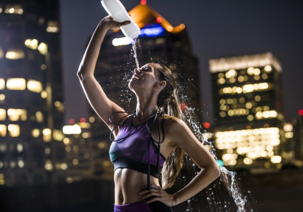 Caucasian woman spraying water on face in city at night