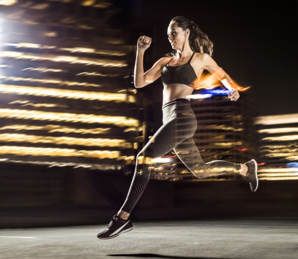 Double exposure of Caucasian woman running in city at night