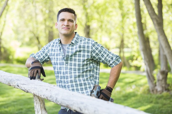 Mixed race man holding drill cleaning on the wooden fence