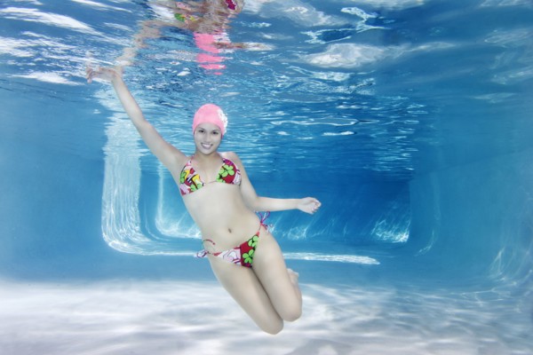 Hispanic woman in bikini swimming underwater