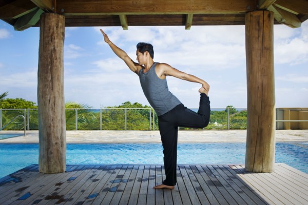 Asian man practicing yoga at poolside