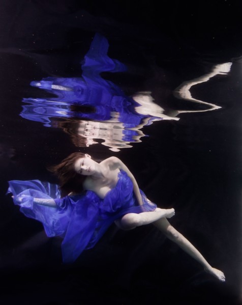 Caucasian woman in dress swimming under water