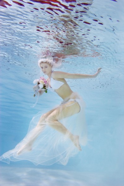 Caucasian bride in bikini swimming under water