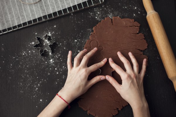 Hand of Caucasian woman pressing pastry cutter into dough