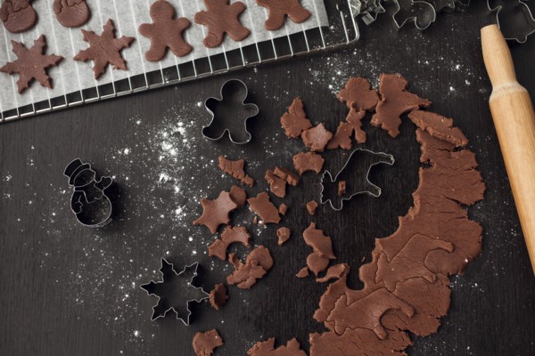 Pastry cutters and gingerbread dough near rolling pin