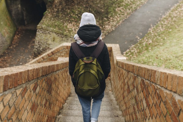 Caucasian woman carrying backpack descending staircase outdoors