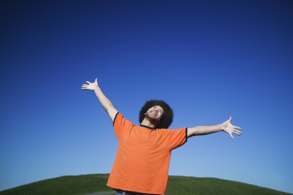 African man with arms raised under blue sky
