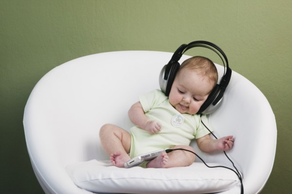 Baby in chair wearing adult headphones