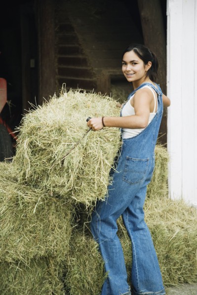 Girl stacking bales of hay