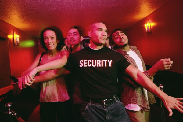 African male bouncer holding back crowd of people