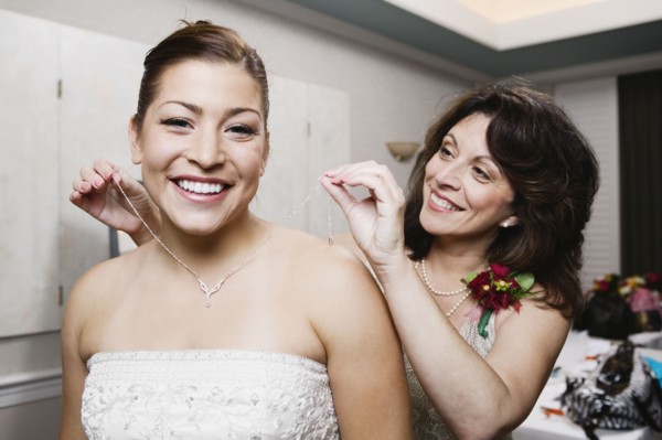 Bride's mother putting necklace on daughter
