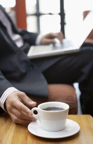 Businessman reaching for cup of coffee