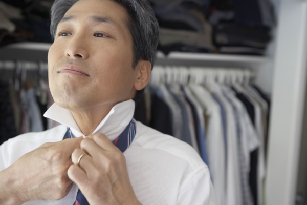 Asian businessman putting on tie