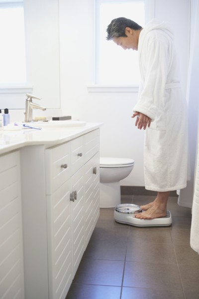 Asian man standing on bathroom scale