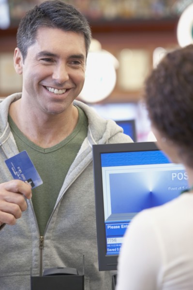 Hispanic man holding up credit card at check out