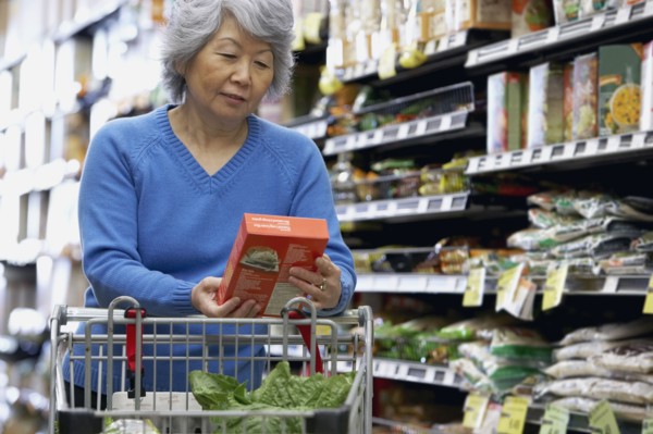 Senior Asian woman reading label at grocery store