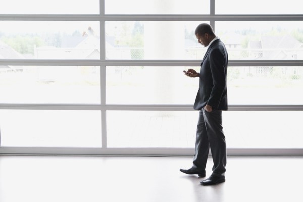African businessman text messaging on cell phone