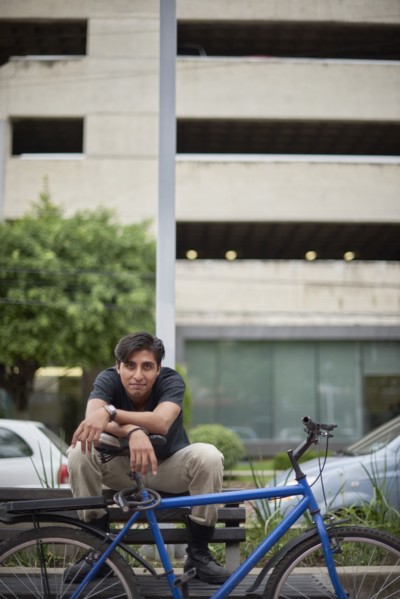 Smiling Hispanic man sitting on bench with bicycle