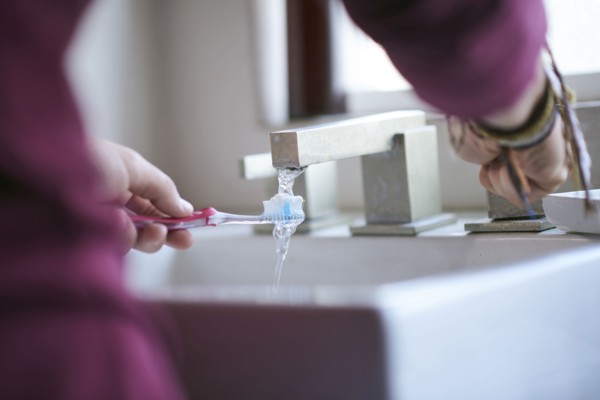Hispanic man wetting toothbrush in sink