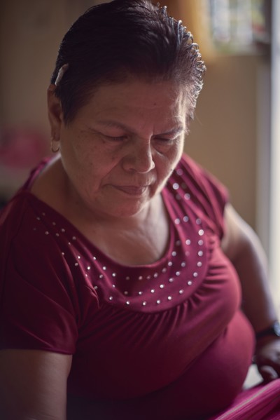 Hispanic woman weaving fabric on loom
