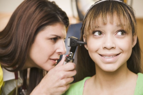 Mixed race doctor examining teenage girl's ears