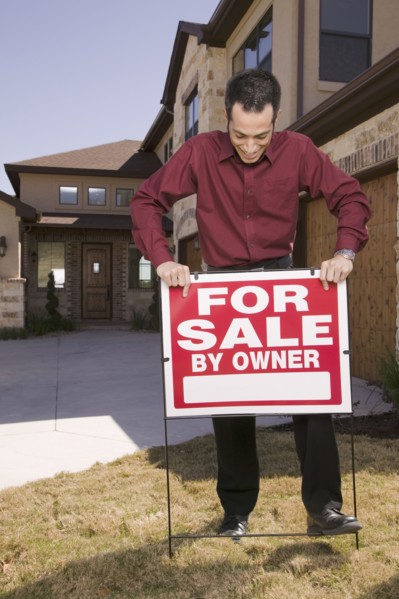 Hispanic man placing for sale sign in yard