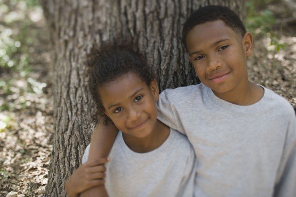 African boy and girl hugging against tree