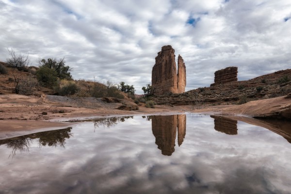 Reflection of rock formation and clouds in puddle