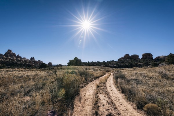 Sun in blue sky over desert path