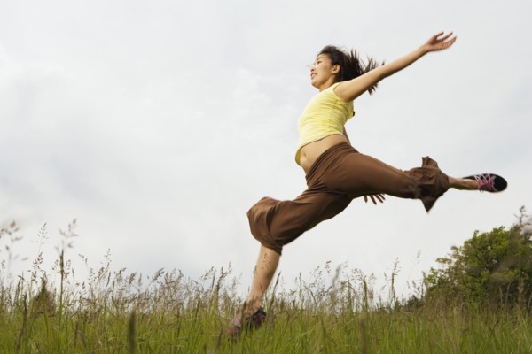 Asian woman jumping in meadow