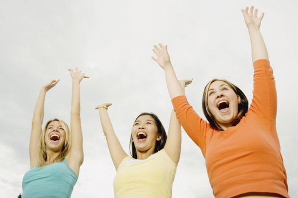 Three woman laughing with arms raised
