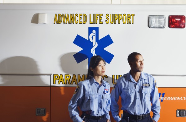 African male and Asian female paramedics next to ambulance