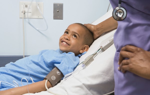 African boy smiling at nurse in hospital bed