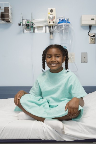 Young African girl sitting in hospital bed smiling