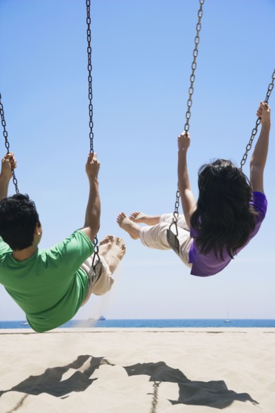 Asian couple swinging at beach