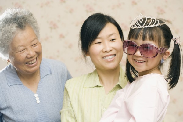 Mother and grandmother smiling at girl in princess costume