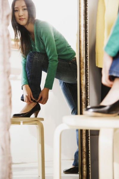 Chinese woman trying on shoes in mirror
